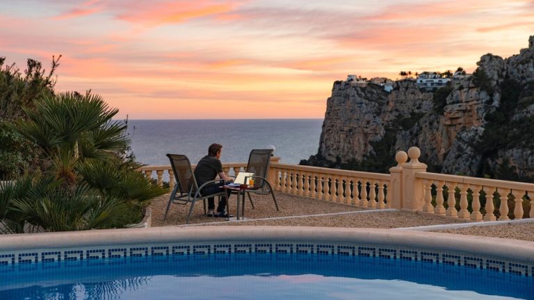 0 Man using his laptop from home terrace looking out of the Mediterranean Sea.jpg